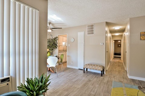 a living room with a couch and a chair and a hallway to a kitchen
